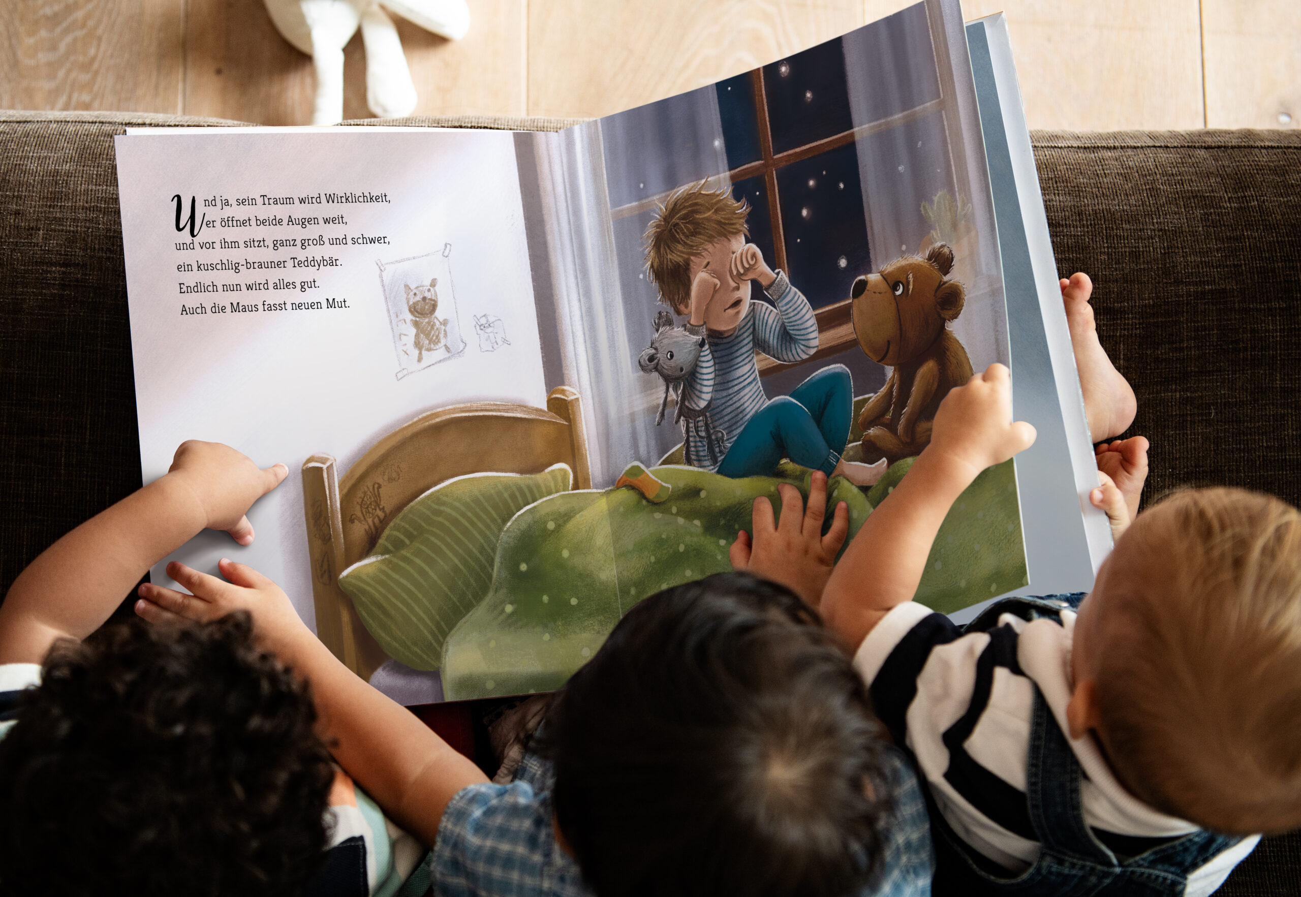 Man sieht drei Kleinkinder aus der Vogelperspektive, die freudvoll im Kinderbuch „Ein starker Freund für Felix“ blättern.